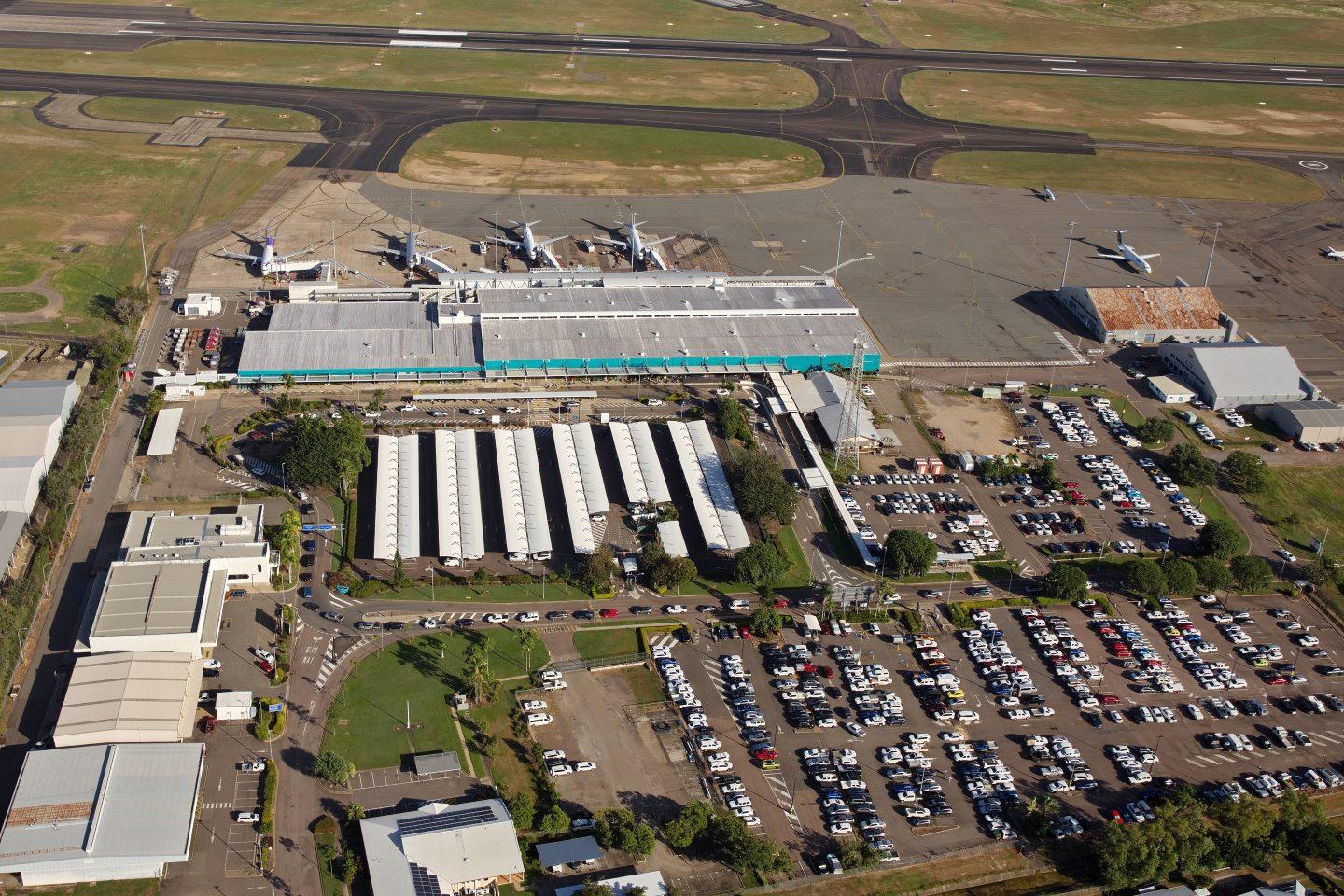 Aerial view of Townsville Airport showing terminal, parked aircraft, parking lots, and surrounding infrastructure.