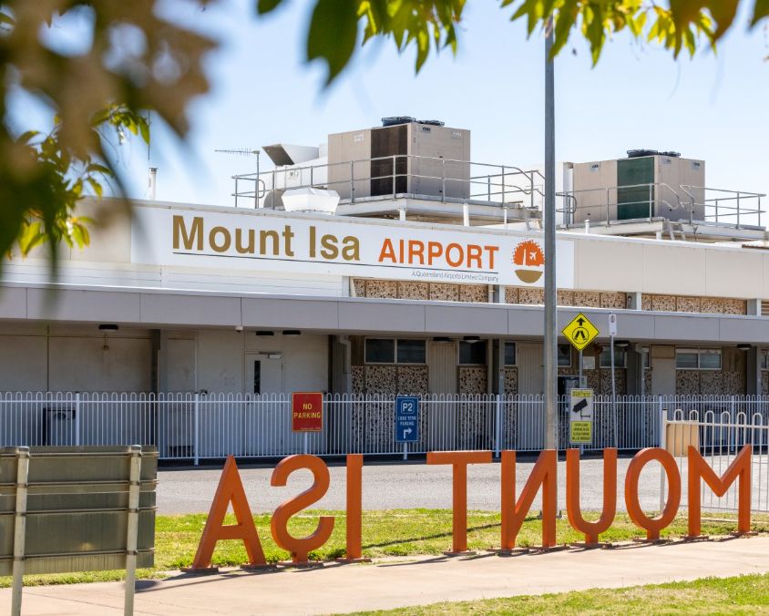 Exterior view of Mount Isa Airport building with signage and air conditioning units.